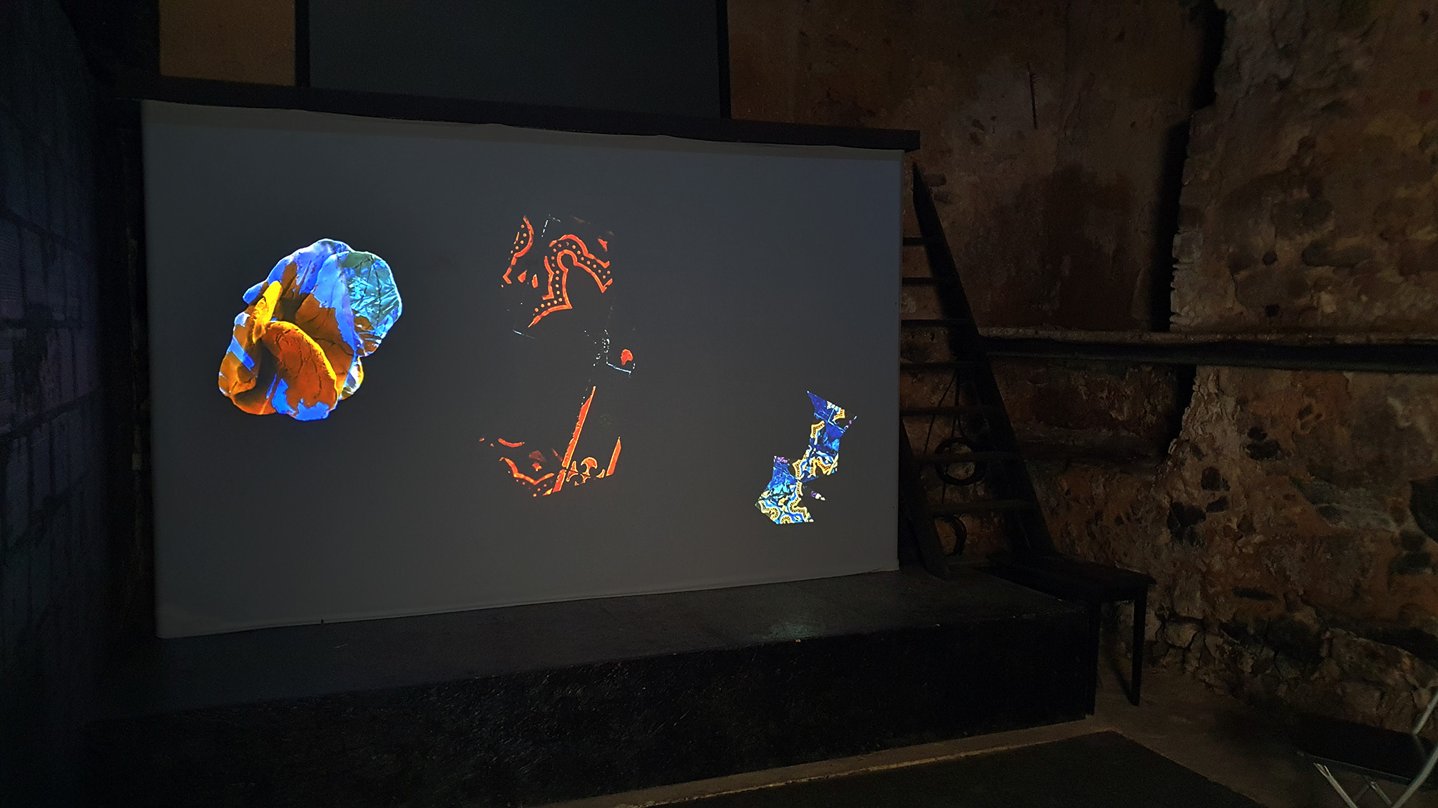 Video of leafy objects on screen in a cave-like dark space
