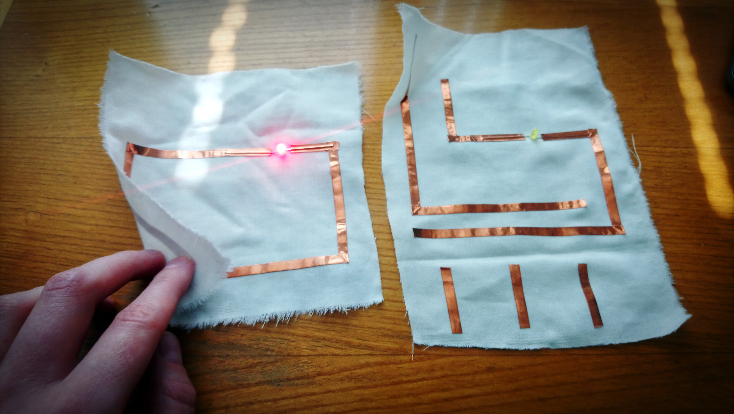 Two fabrics with copper tape as a circuit, one of the fabrics is touched and LED light is on.