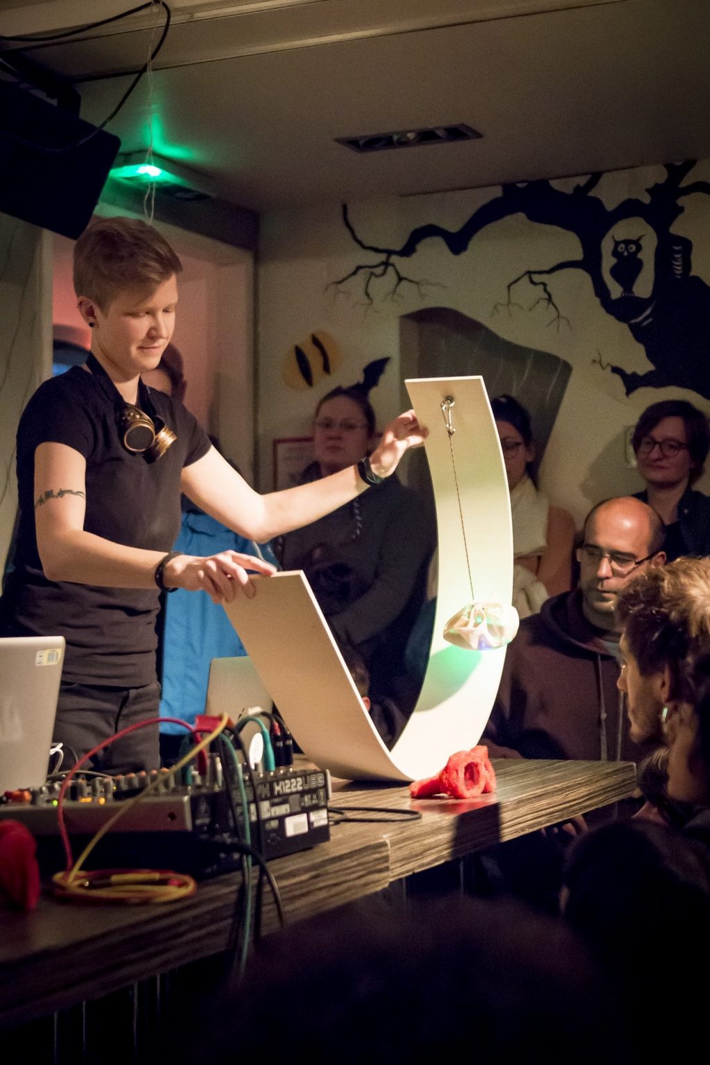 A person (me) holding the wooden curve object on the table in front of the audience.